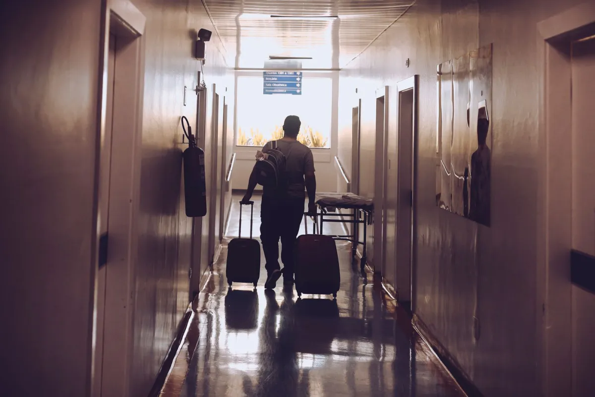 Traveler pulling two rolling suitcases down a hotel corridor