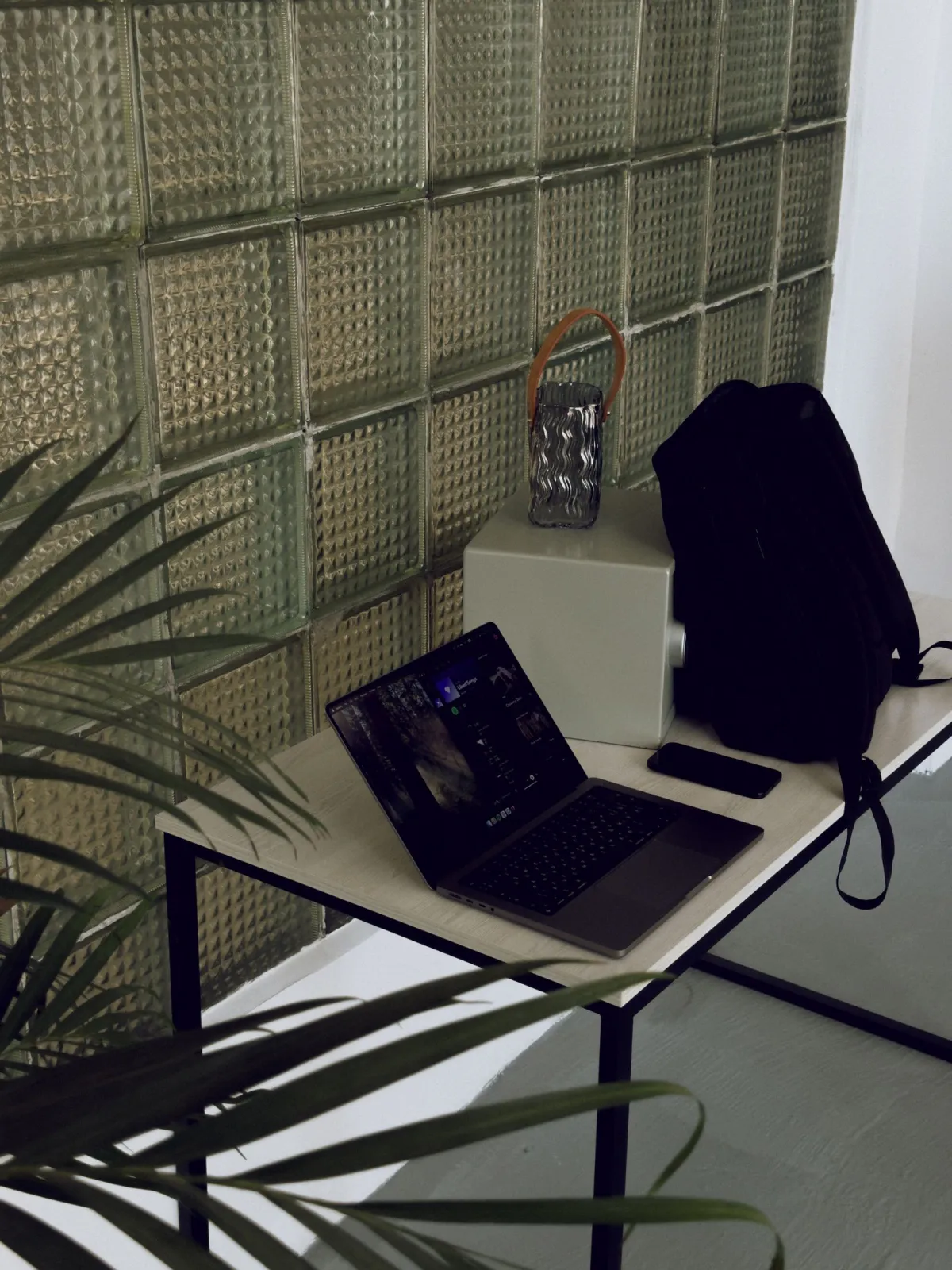 Black backpack standing on a desk beside an open laptop
