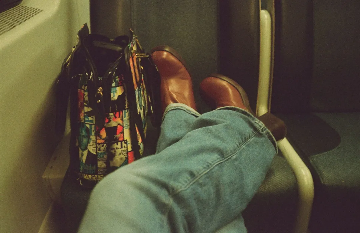 Graphic print bag sitting on a passenger seat next to a traveler's feet