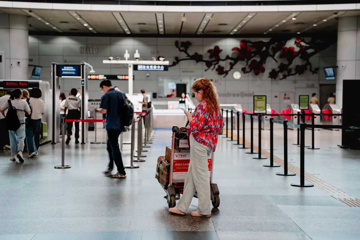 Traveller with a loaded luggage cart waiting in an airport check-in hall