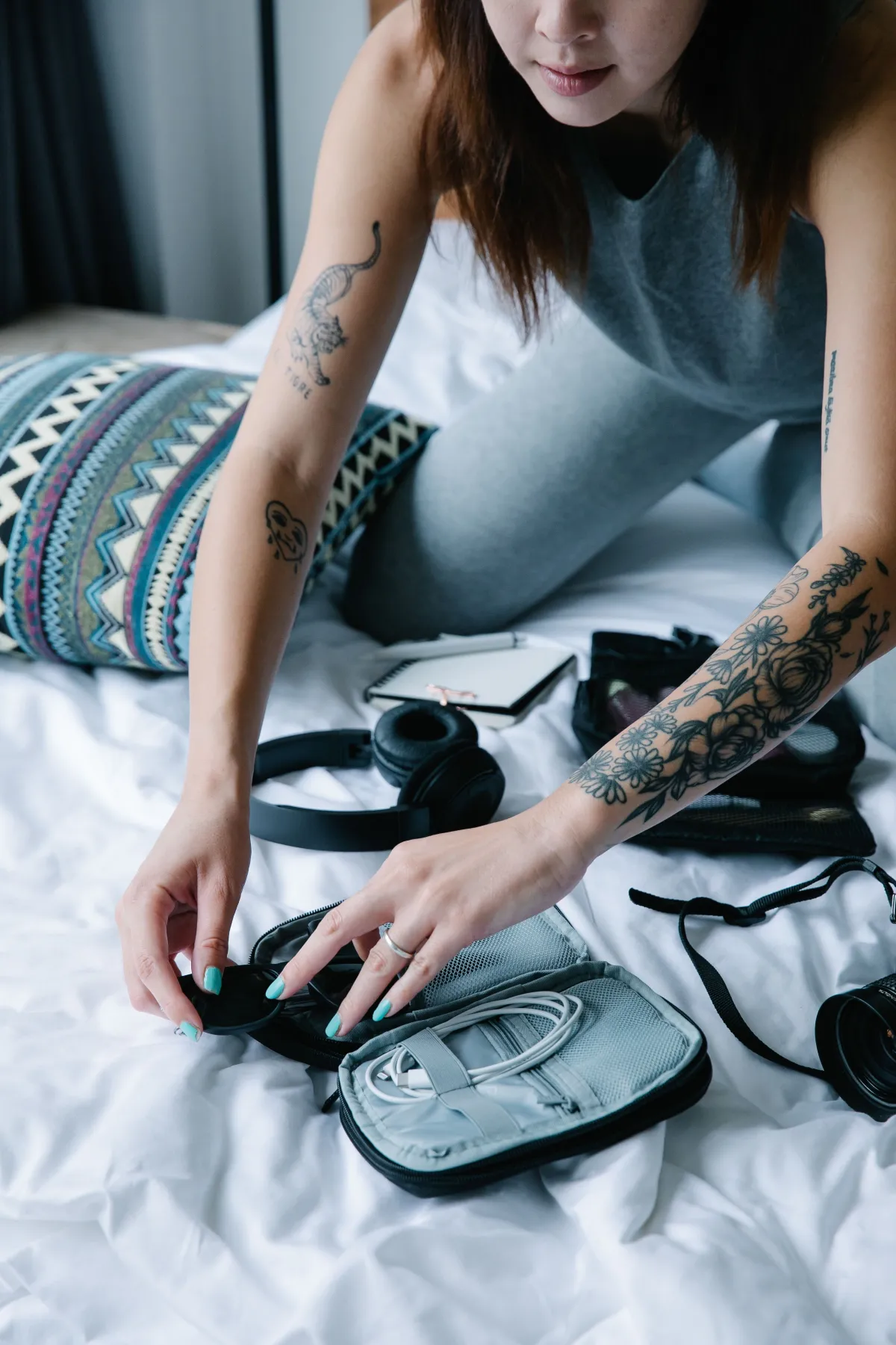 Open cable organizer beside headphones and a notebook on a bed.