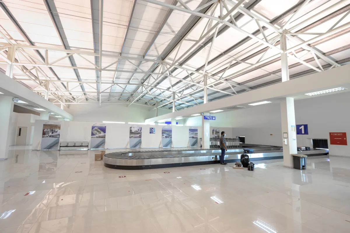 Traveler standing beside a baggage carousel with several bags nearby.