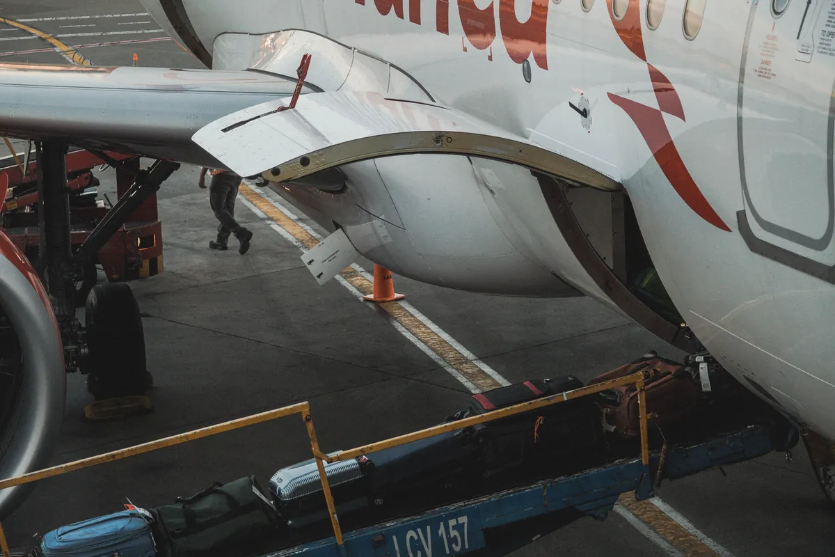 Checked suitcases riding a belt loader up into the hold of a passenger jet.