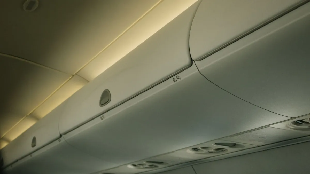 Close view of closed overhead bins in an airplane cabin under soft yellow lighting